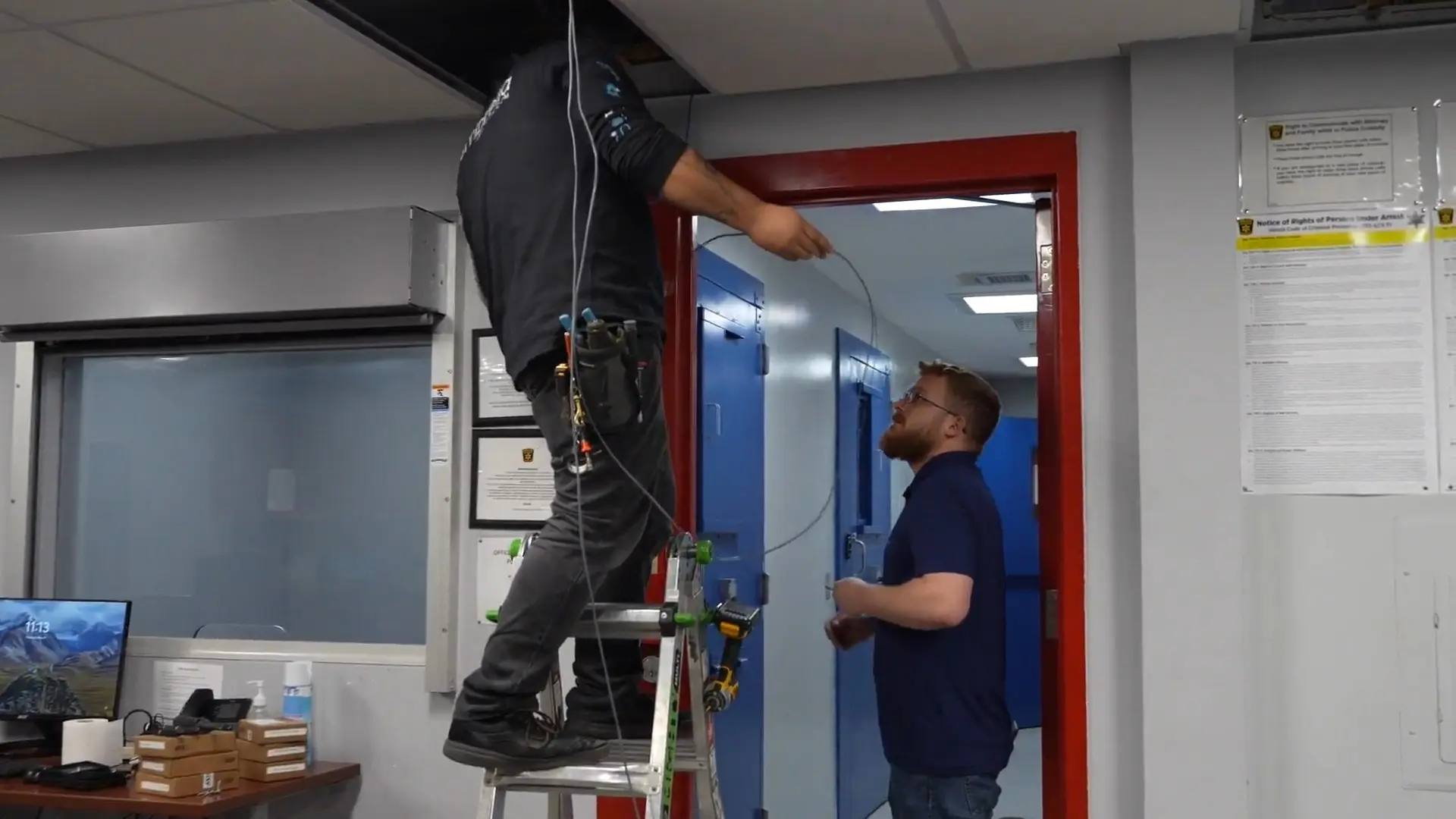 Wilmington Police and City Hall Security Modernization 6 Umbrella Security technicians running camera cabling above a doorway inside the working Wilmington police station
